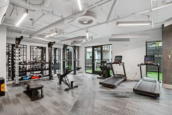 A workout room with treadmills and other equipment in a building with white walls